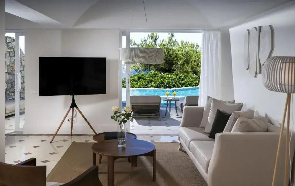 Luxuriöses Wohnzimmer mit Sofas und Blick auf privaten Pool und Garten.