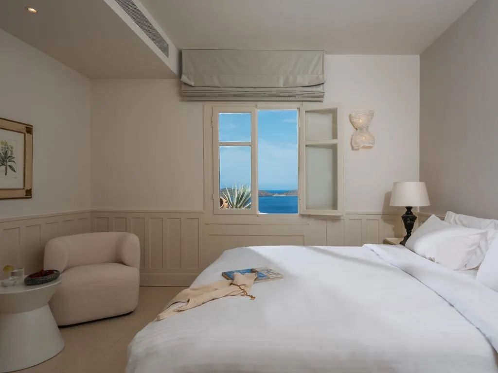 Modernes Schlafzimmer mit bequemen Bett und Meerblick aus dem Fenster