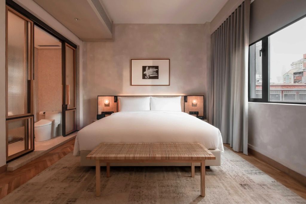 Modernes Standardzimmer mit großem Bett und Holzbank in neutralen Tönen