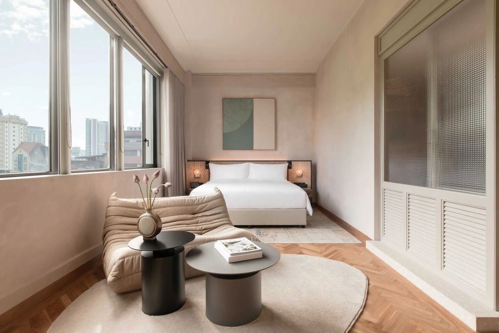 Helles Zimmer mit großem Bett, gemütlicher Sitzgelegenheit und großer Fensterfront