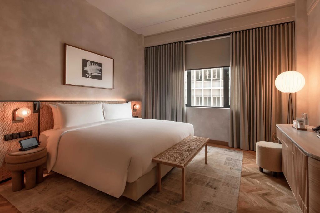 Elegantes Zimmerdesign mit großem Bett, hellem Teppich und dezenter Beleuchtung