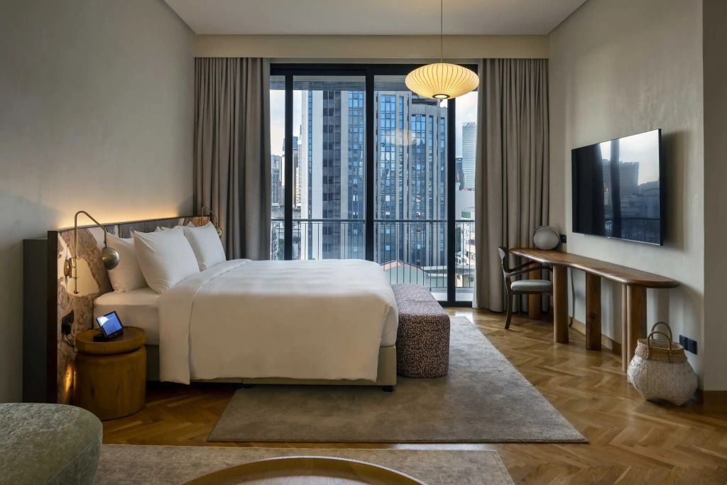 Zimmer mit Doppelbett und bodentiefen Fenstern zur Stadtansicht