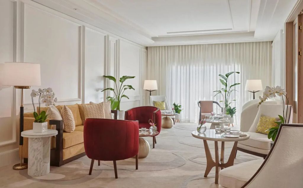 Geräumige Hotelsuite mit roten Sesseln und natürlichen Pflanzenakzenten