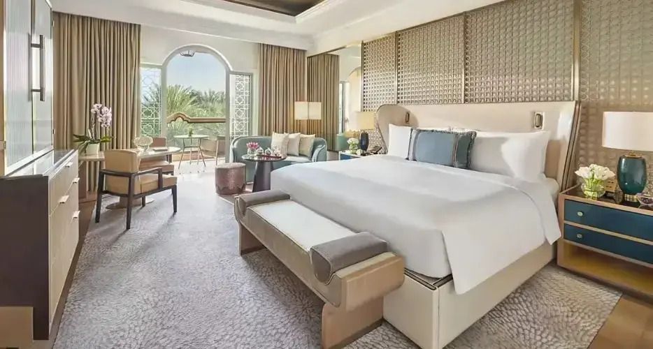 Suite mit Doppelbett und Balkon mit Ausblick auf Palmen.