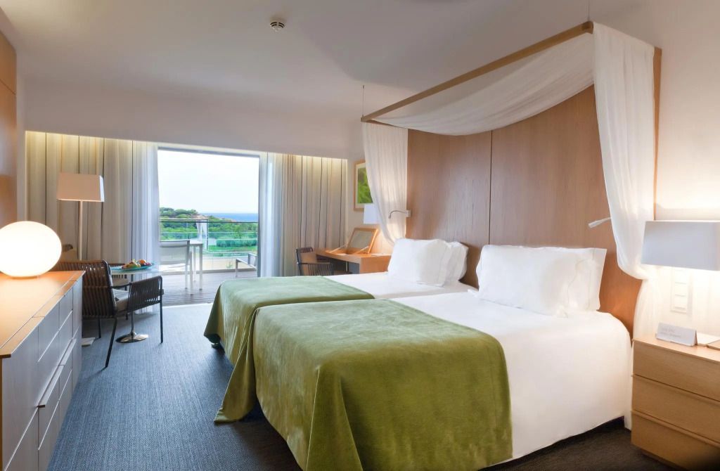Helles Schlafzimmer mit Doppelbett und Zugang zum Balkon mit Gartenblick