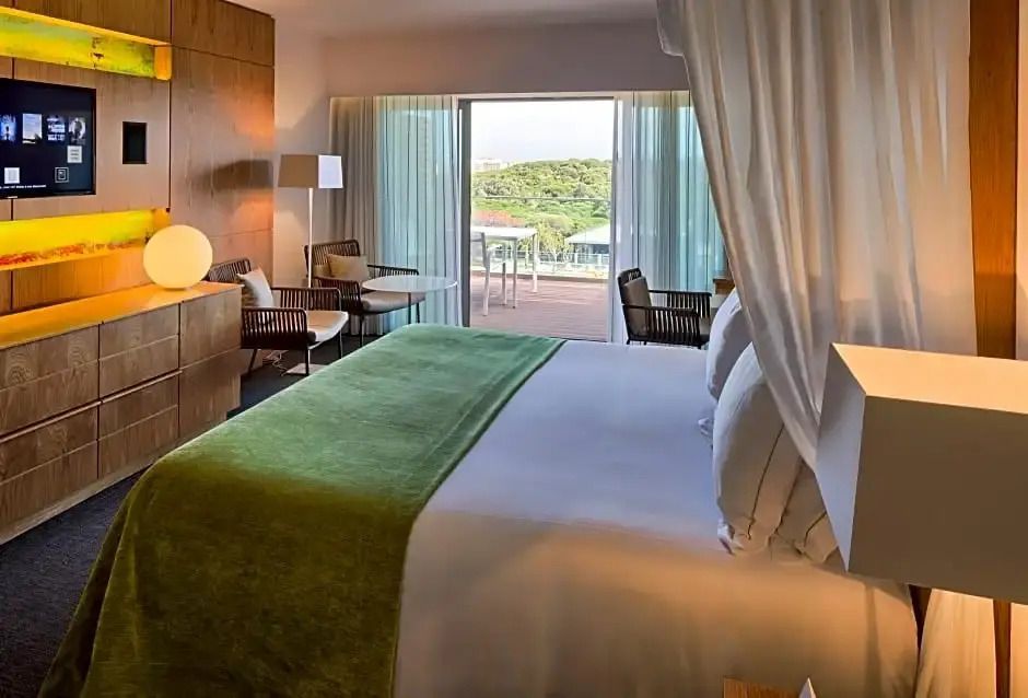 Helles Schlafzimmer mit großem Doppelbett und grünem Dekor sowie Blick auf den Balkon