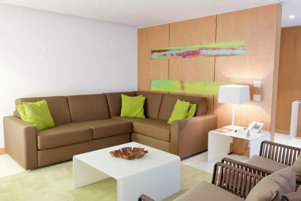 Modernes Wohnzimmer in Deluxe Suite mit braunem Sofa und grünen Akzenten