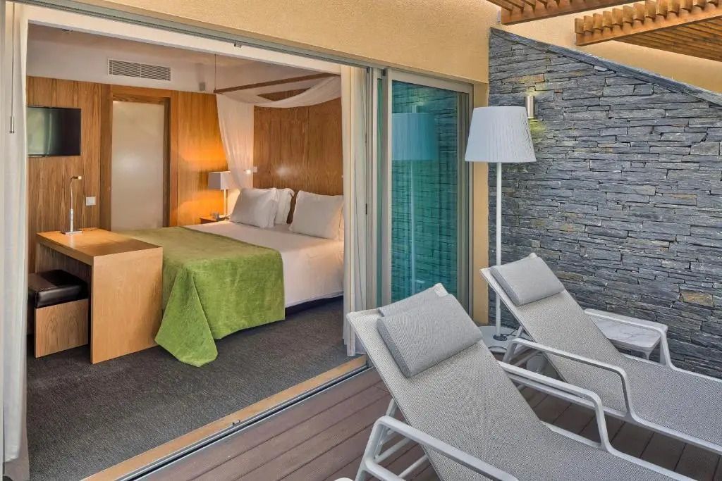 Schlafzimmer mit großem Bett und Zugang zur Terrasse in Deluxe Suite