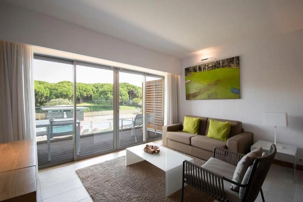 Wohnbereich der Junior-Suite mit großen Fenstern und Terrasse mit Gartenblick.