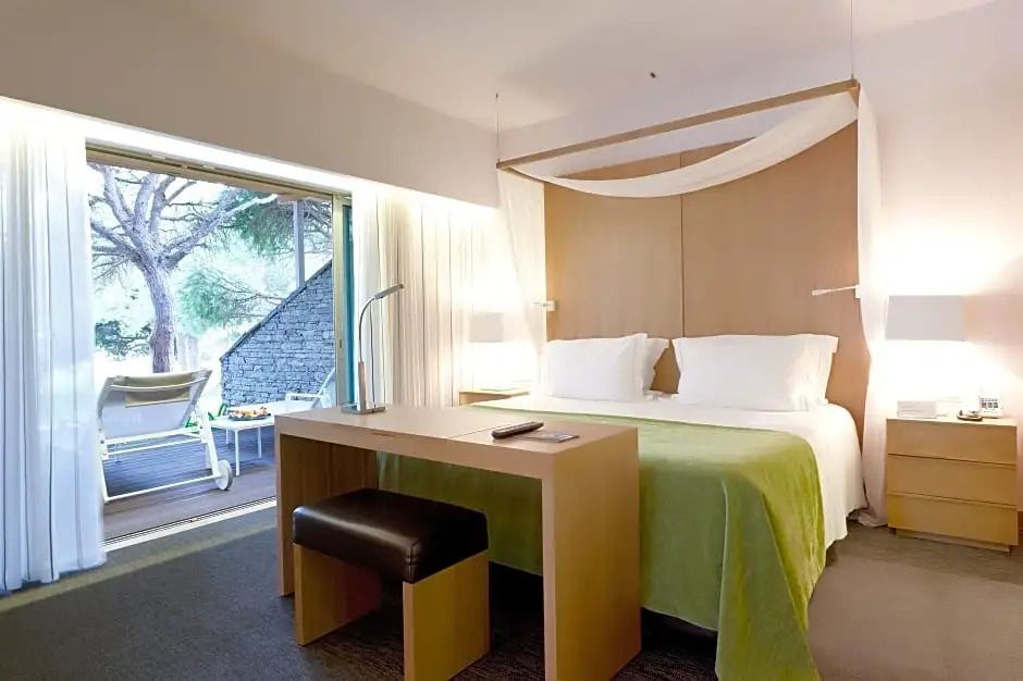 Schlafzimmer mit Schreibtisch und direktem Zugang zur Terrasse im Standard Apartment.