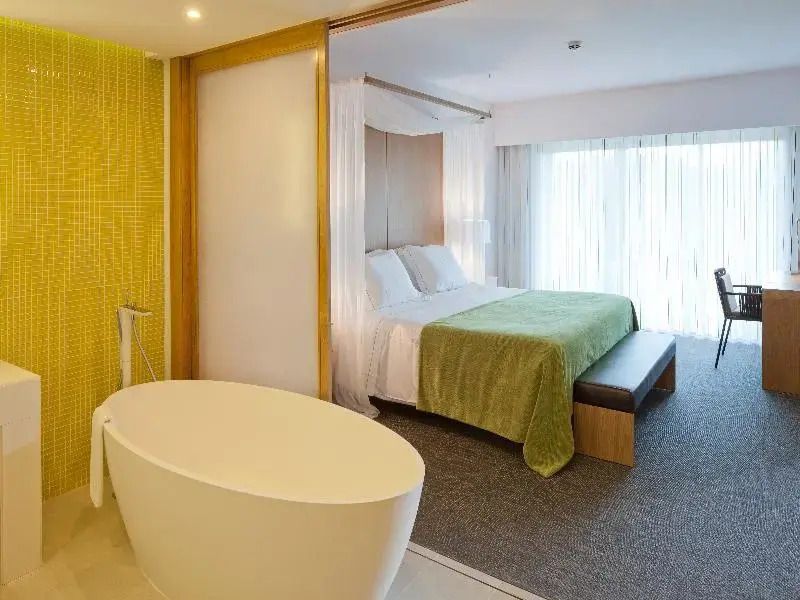 Hotelzimmer mit modernem Bad und Badewanne neben einem Bett im Epic Sana Algarve
