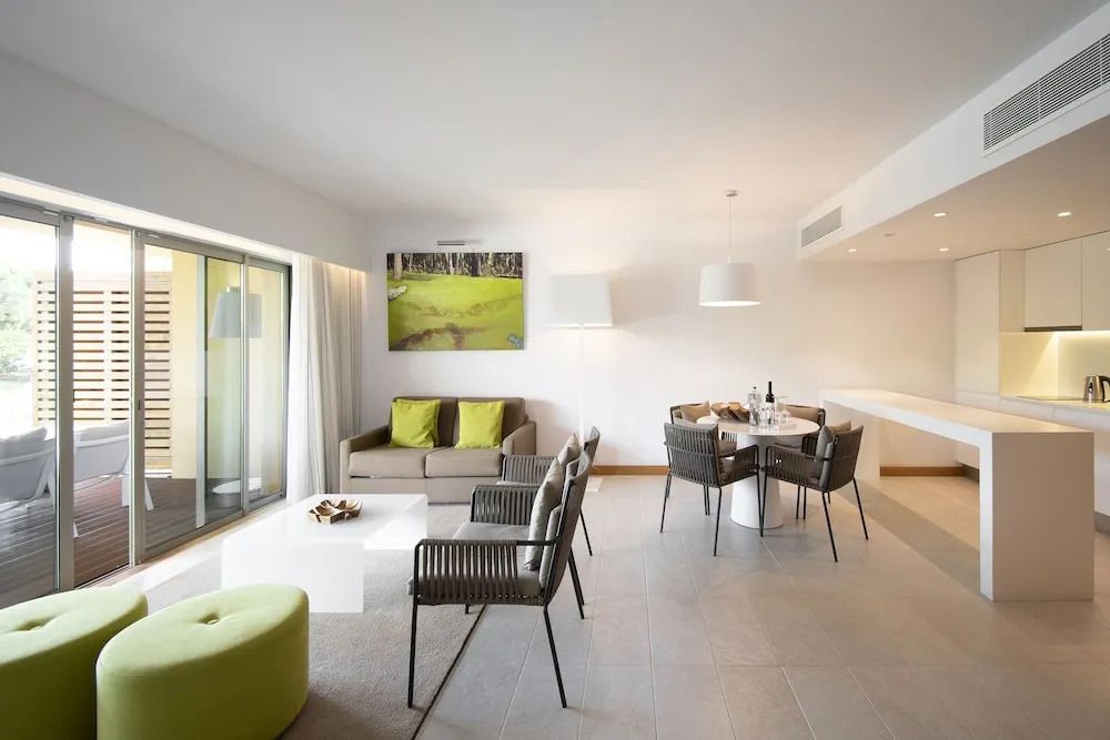 Moderne Suite mit Gartenblick. Sitzbereich mit Couch, Sesseln und Esstisch.