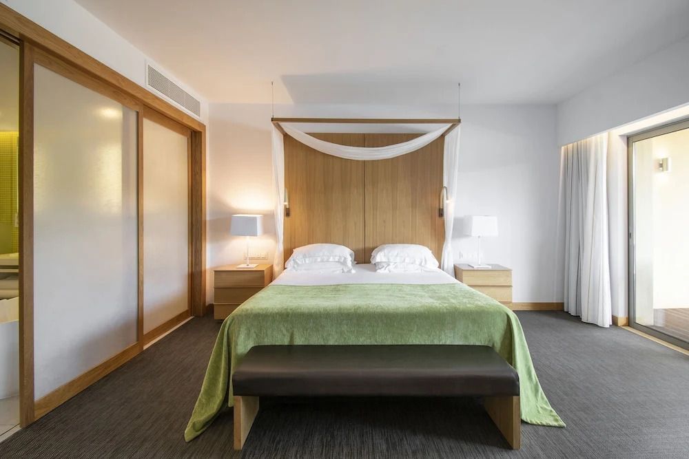 Luxuriöse Suite mit großem Bett, grüner Decke und Nachttischen.