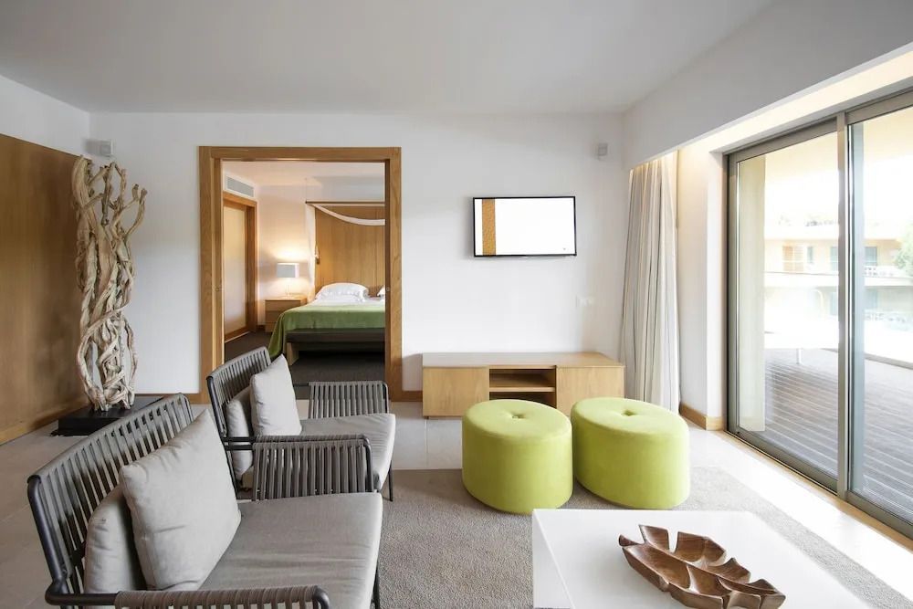 Sitzbereich in der Suite mit zwei Sesseln und grünem Hocker. Zugang zum Schlafzimmer.