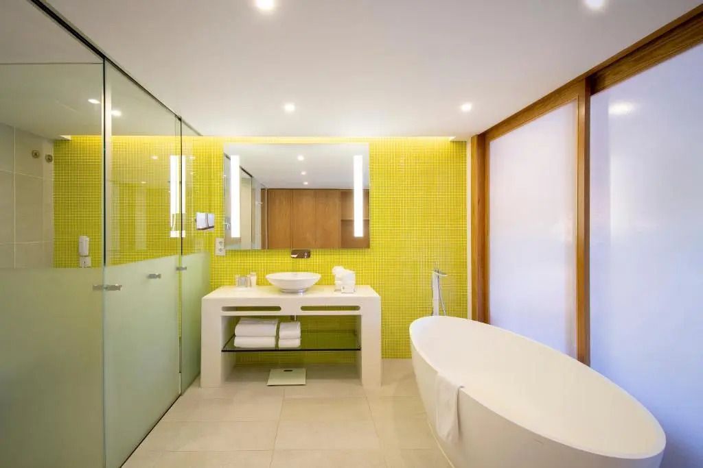 Modernes Badezimmer in der Suite mit freistehender Badewanne und großem Spiegel