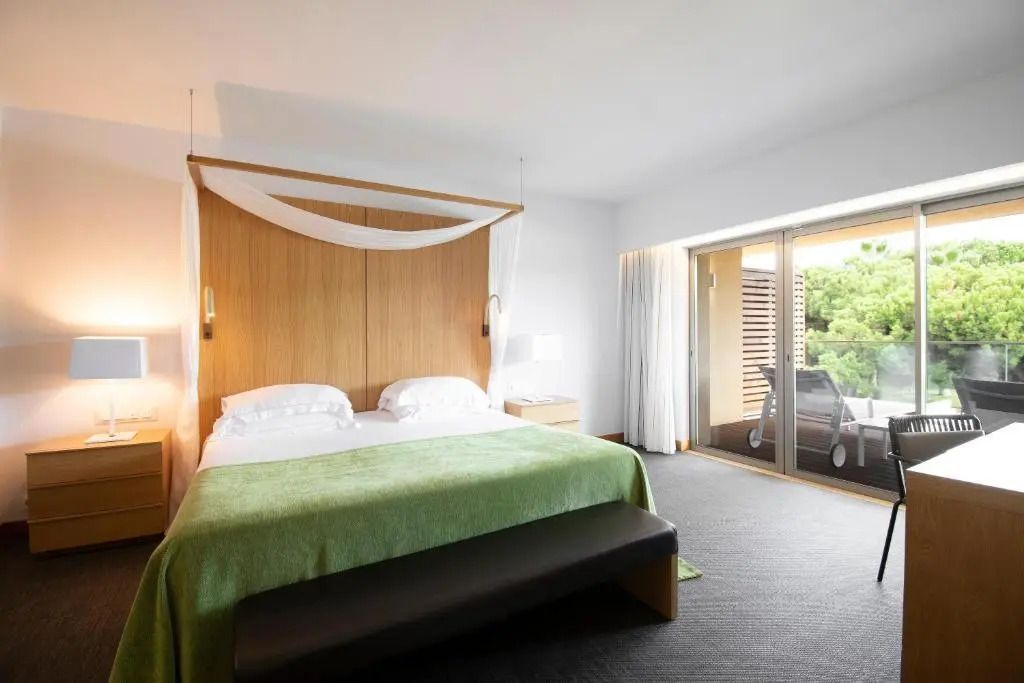 Zimmeransicht mit großem Bett und Zugang zum Balkon im Hintergrund