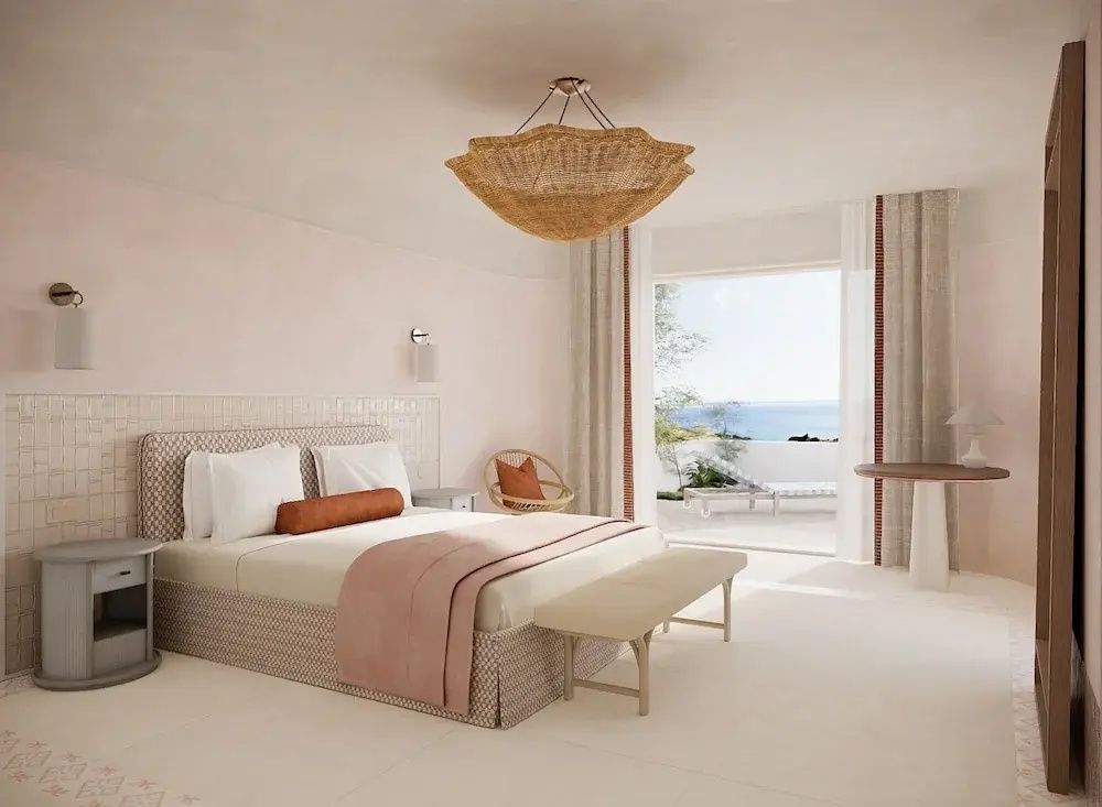 Helles Schlafzimmer mit Doppelbett in einer Suite und Blick auf das Meer durch große Fenster