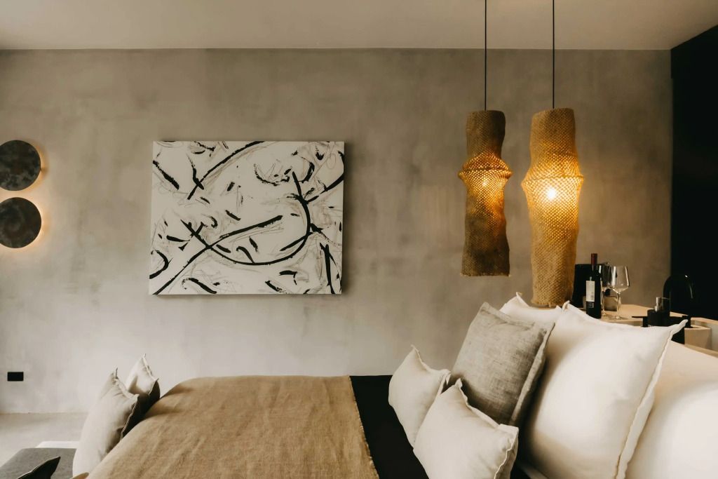 Detailaufnahme eines Bettes mit stilvollen Hängelampen und Kunstwerk
