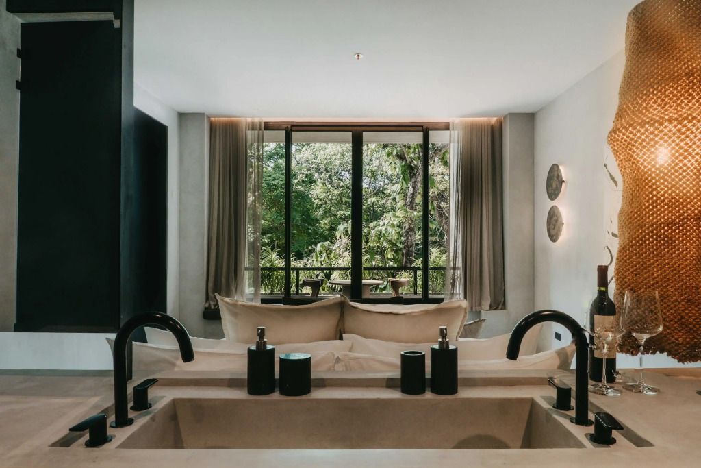 Freistehende Badewanne mit Ausblick auf grün bewachsenen Balkon