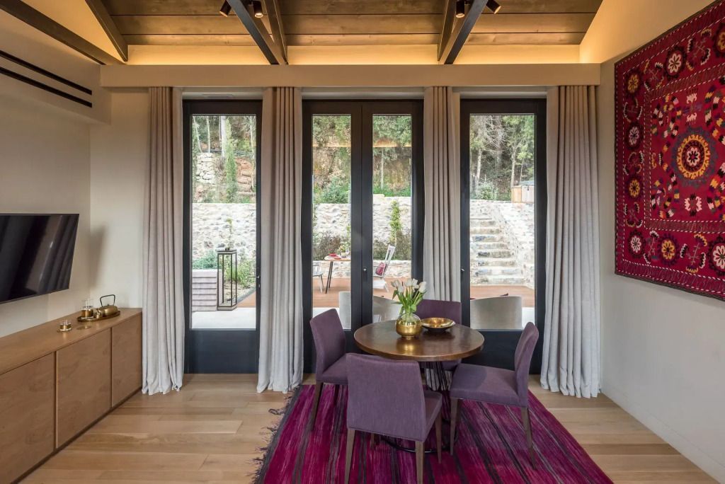 Elegantes Wohnzimmer in einer Suite mit runden Tisch und vier Stühlen auf einem roten Teppich.