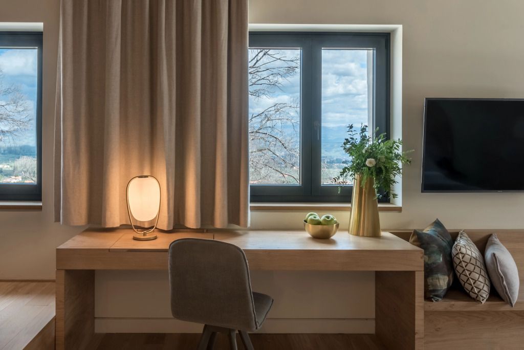 Schreibtischbereich mit dekorativer Lampe und Fensterblick auf die Natur