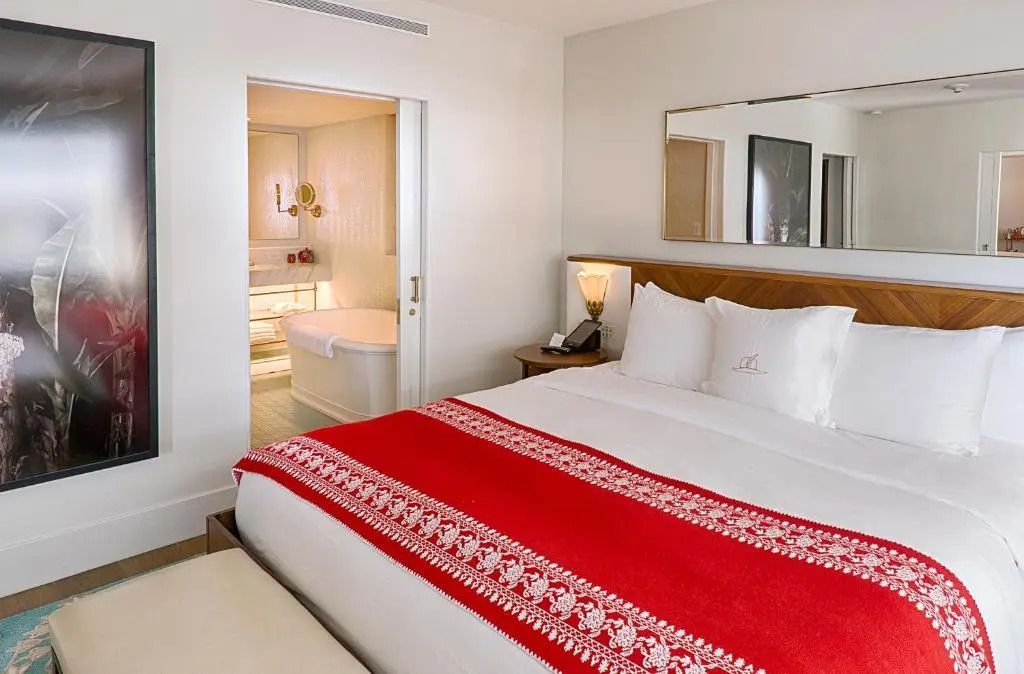 Geräumiges Doppelbett in einer Suite mit einer angrenzenden, eleganten Badewanne.
