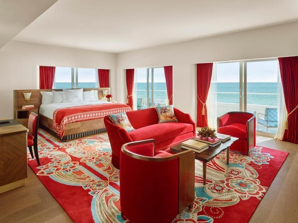 Luxuriöses Schlafzimmer mit Meerblick, roten Akzenten und eleganten Möbeln.
