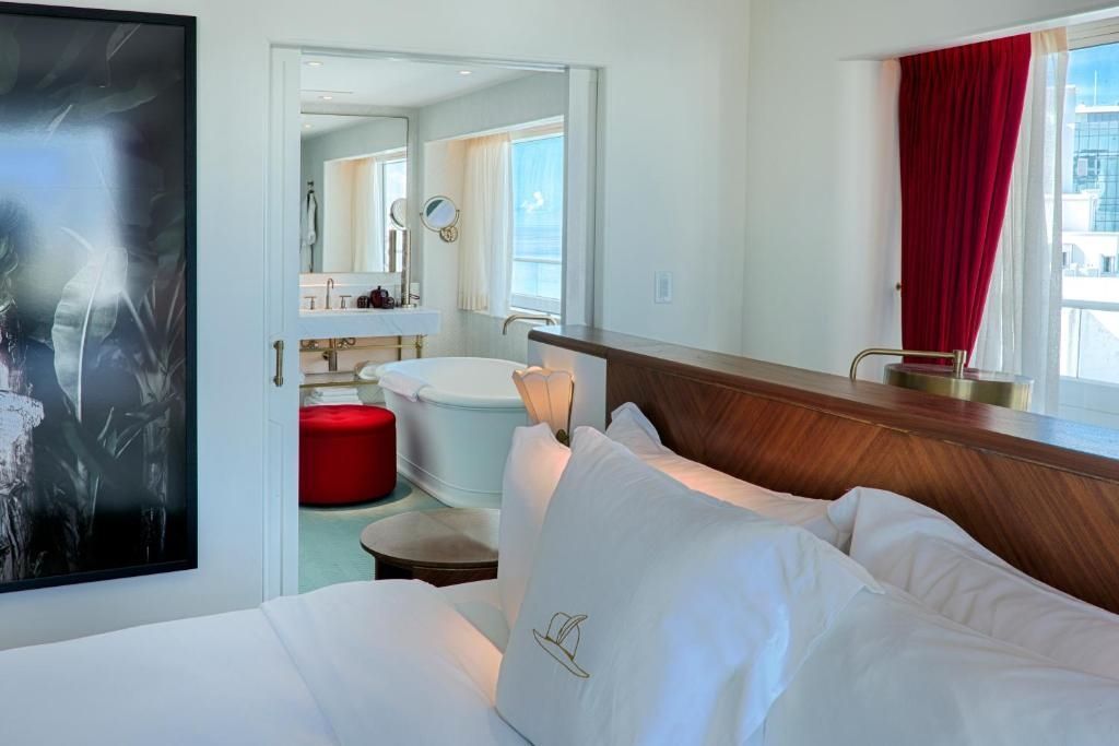 Blick vom Bett auf luxuriöses Badezimmer mit freistehender Badewanne