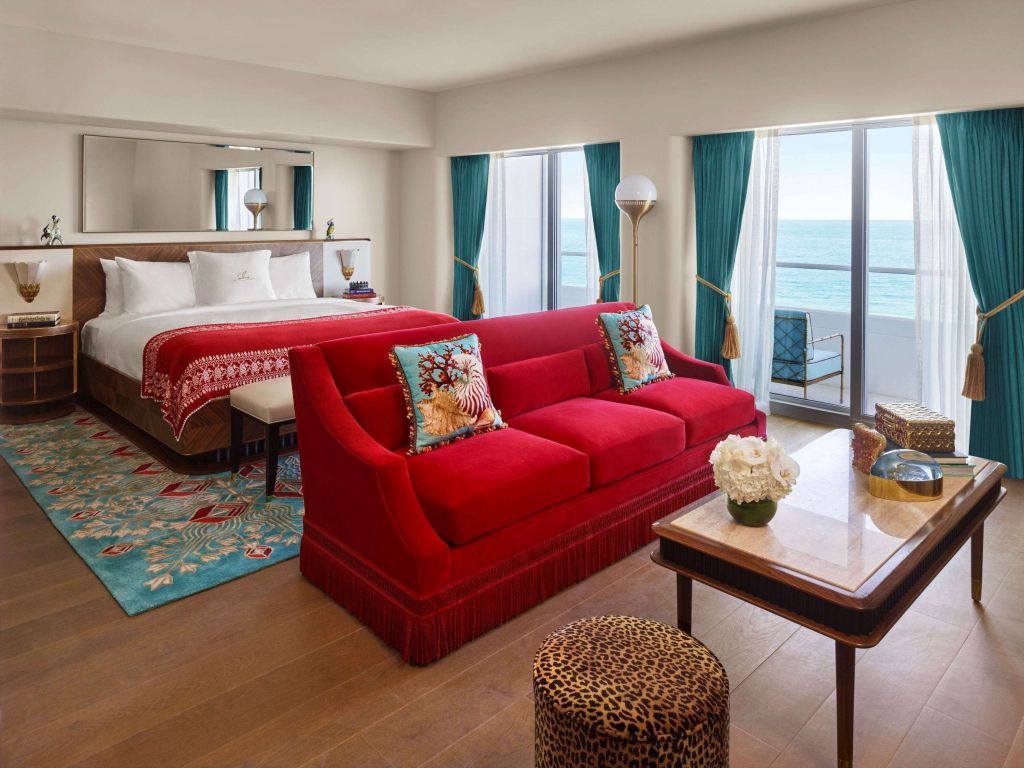 Luxuriöses Hotelzimmer mit rotem Sofa und Meerblick vom Balkon