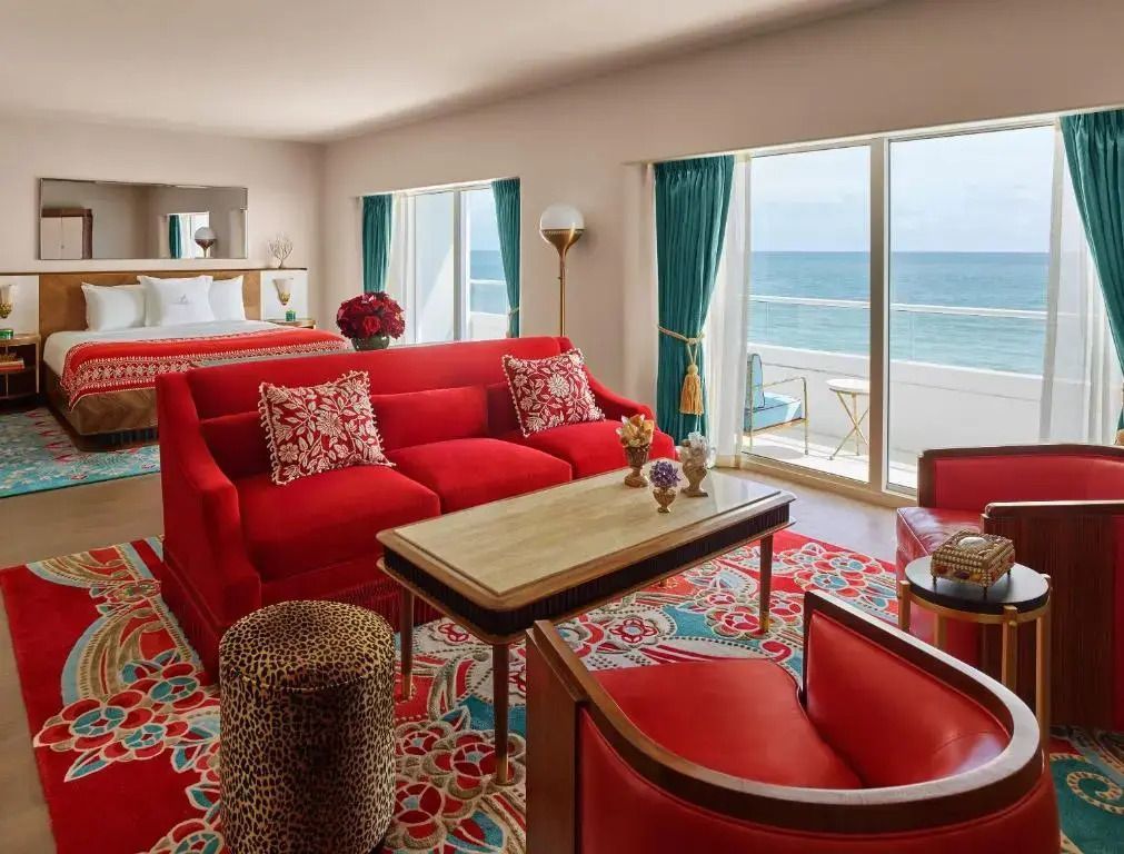 Helles Hotelzimmer mit rotem Sofa und weitem Meerblick