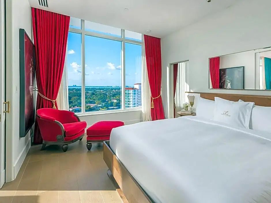 Helles Schlafzimmer mit Panoramafenster und Blick auf die Bucht, rote Vorhänge
