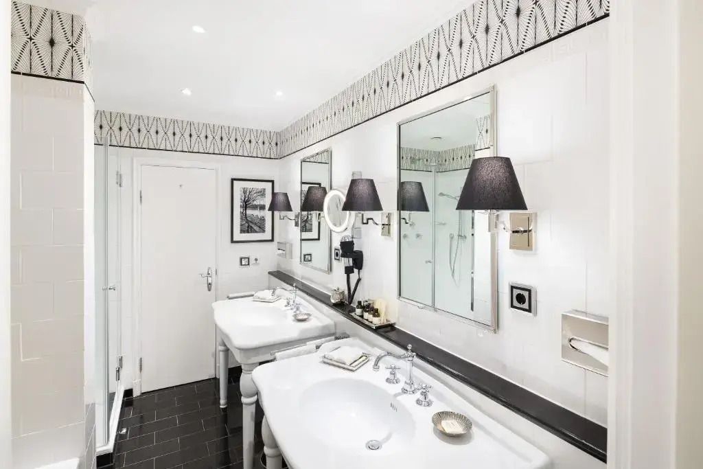 Modernes Badezimmer mit zwei Waschbecken und stilvollen Wandlampen in der Deluxe Doppel Suite