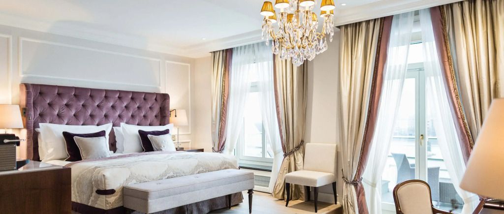 Elegantes Zimmer mit Doppelbett, Kronleuchter und großen Vorhängen