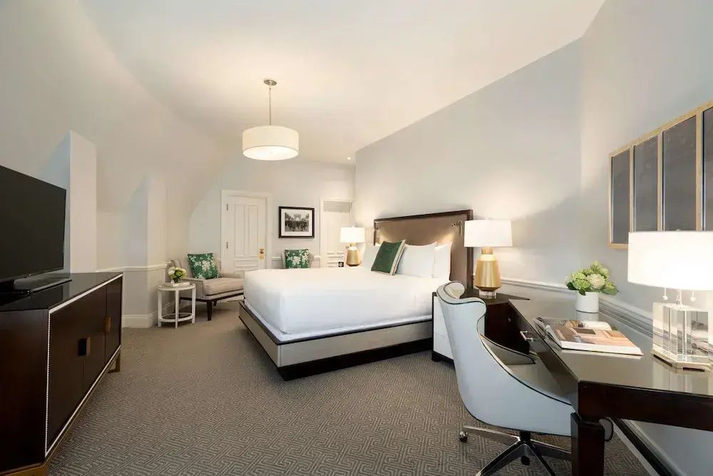 Luxuriöses Schlafzimmer mit Kingsize-Bett und Schreibtisch in der Charles de Gaulle Suite.