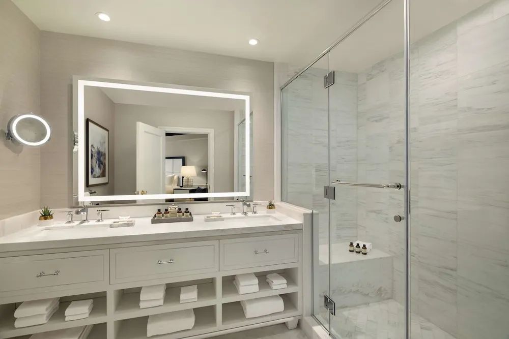 Modernes Badezimmer mit großer Spiegelwand und Glasdusche in der Charles de Gaulle Suite.