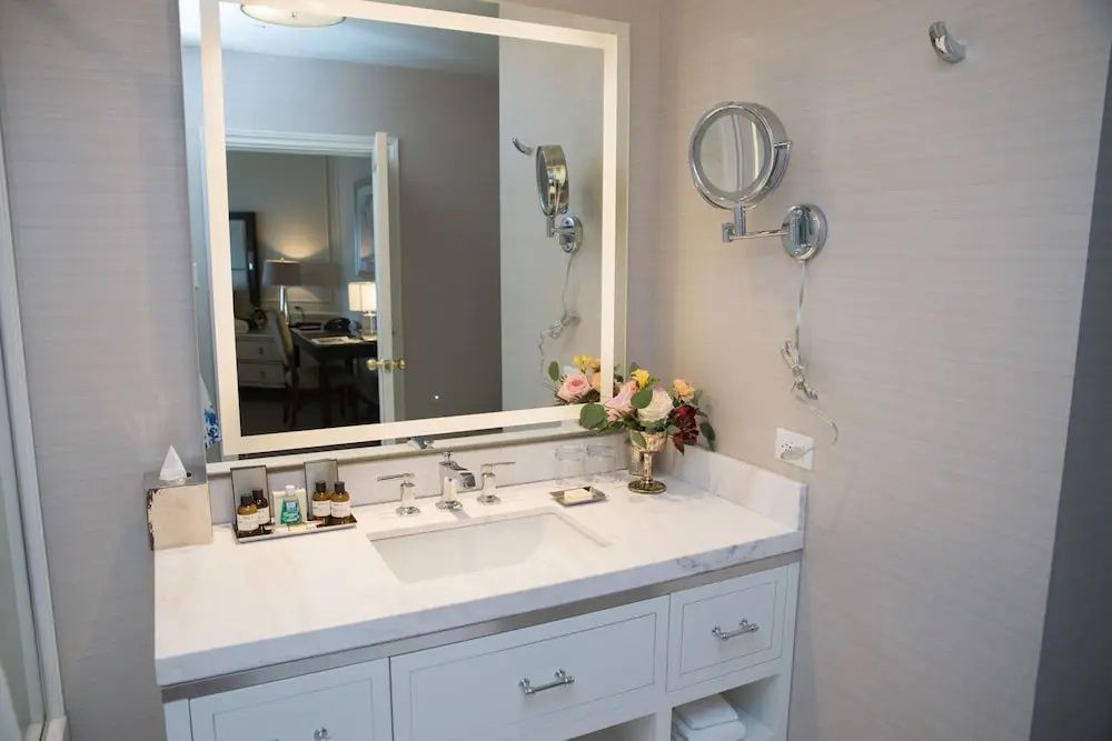 Moderne Badezimmer Waschtisch mit Blumenarrangement und beleuchtetem Spiegel