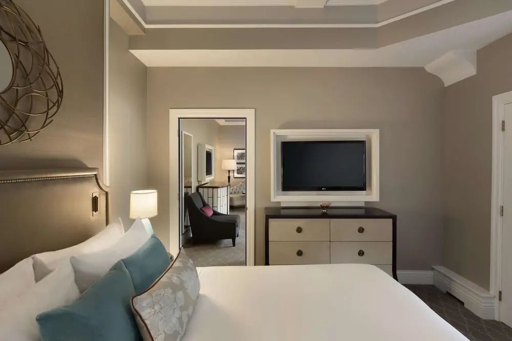 Elegantes Schlafzimmer der Frontenac Suite mit gemütlichem Bett und Flachbildfernseher.