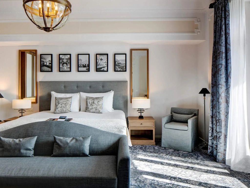 Komfortables Schlafzimmer mit grauem Sofa und stilvollen Wandbildern im Fairmont Le Montreux Palace