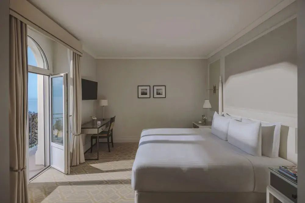 Helles Schlafzimmer der Junior-Suite mit Doppelbett und Schreibtisch, Seeblick durch Fenster.