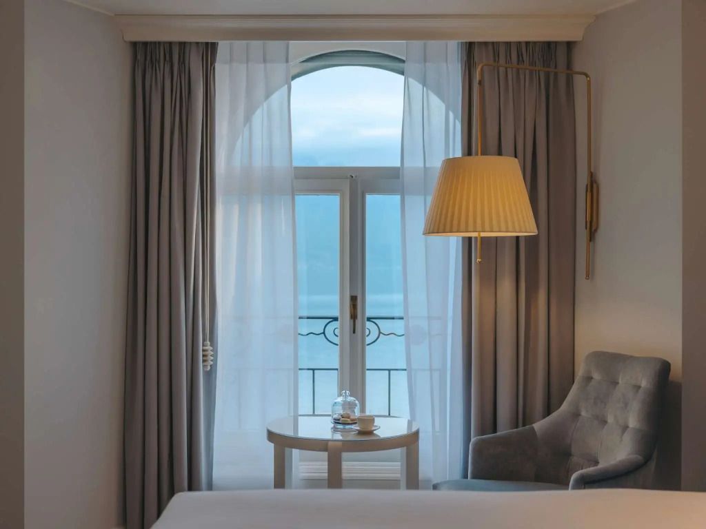 Fenster mit Vorhängen im Fairmont Zimmer, Blick auf den See und gemütlicher Sessel.