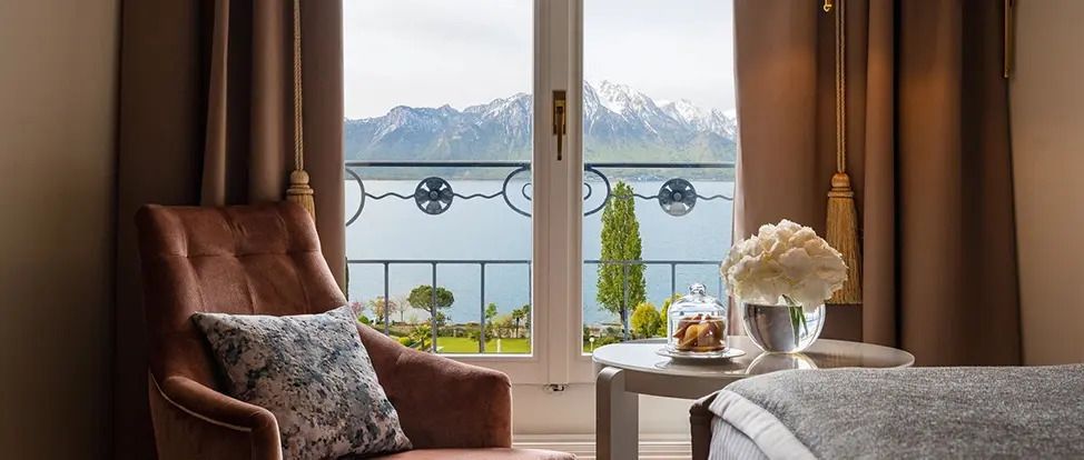 Blick aus einem Zimmer auf den Genfersee und schneebedeckte Berge. Elegantes Interieur.