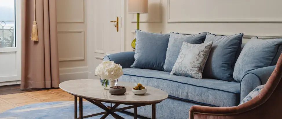 Gemütliche Sitzecke mit blauer Couch, Kissen und stilvollem Couchtisch.