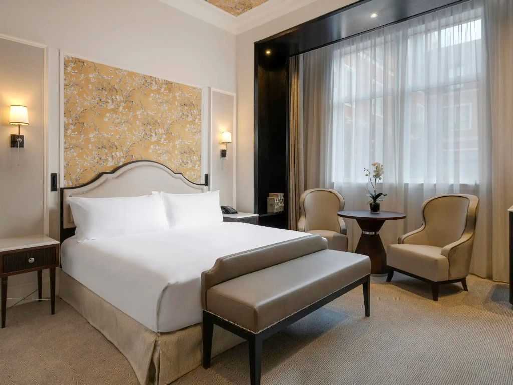 Hotelzimmer mit luxuriösem Doppelbett, floralen Tapeten und gemütlichen Möbeln.