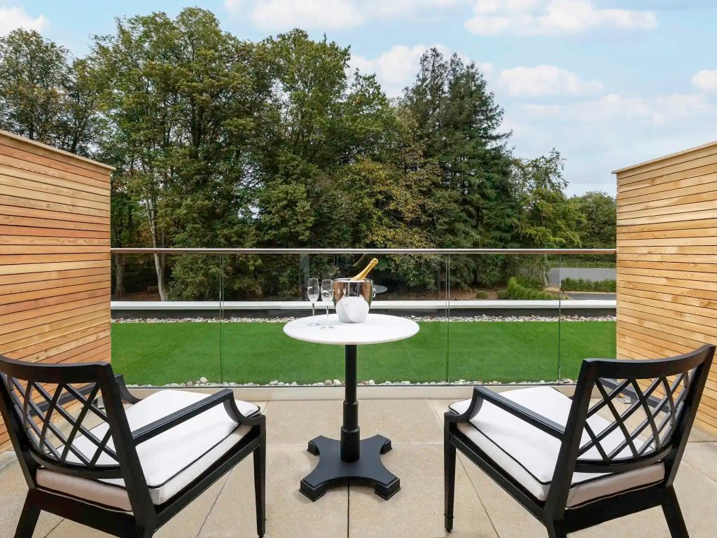 Balkon mit Sitzbereich und Ausblick ins Grüne im Fairmont Hotel Windsor Park.