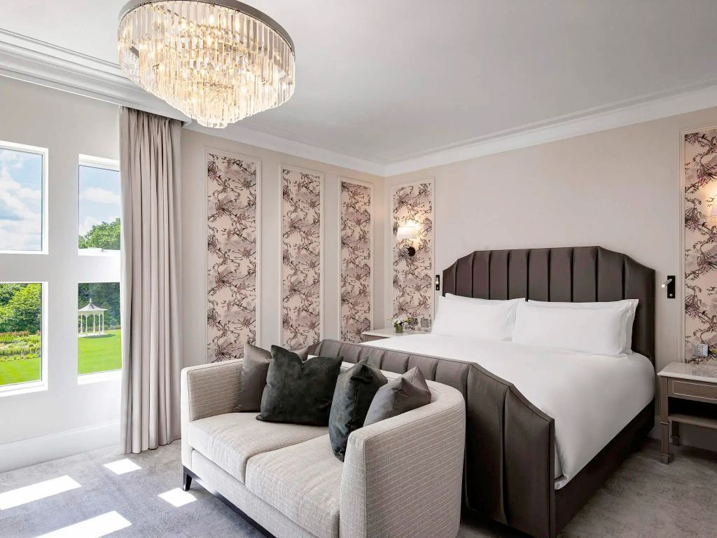 Elegantes Schlafzimmer mit großem Bett, bequemer Couch und raffinierter Beleuchtung
