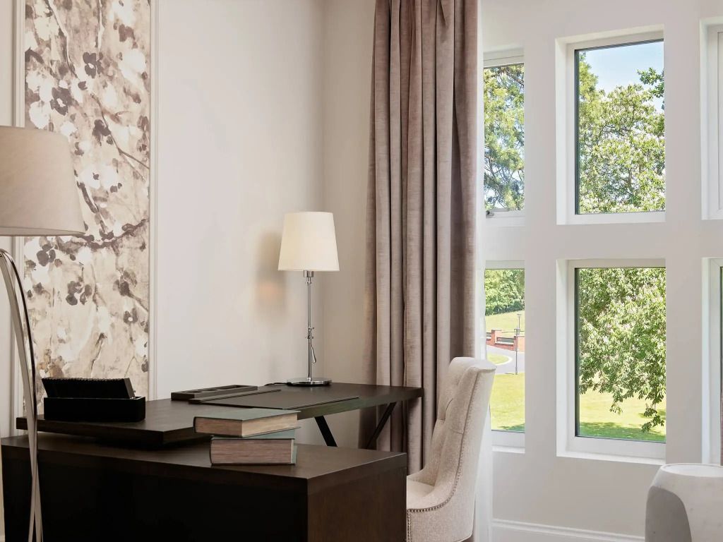Arbeitsbereich mit Schreibtisch und Fenster mit Blick auf grüne Landschaft