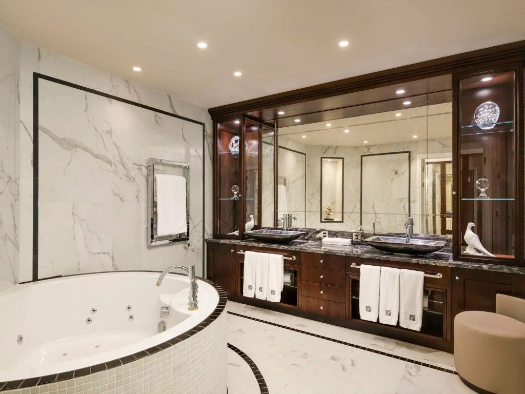 Elegantes Badezimmer mit Whirlpool, Doppelwaschbecken und hochwertiger Marmorverkleidung.