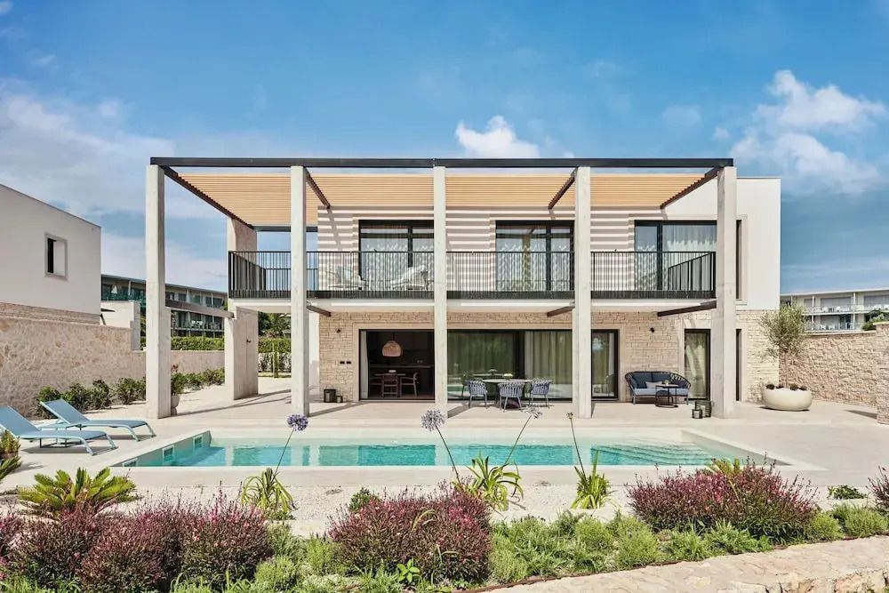 Moderne Luxusvilla mit großer Terrasse und Pool in grüner Umgebung.