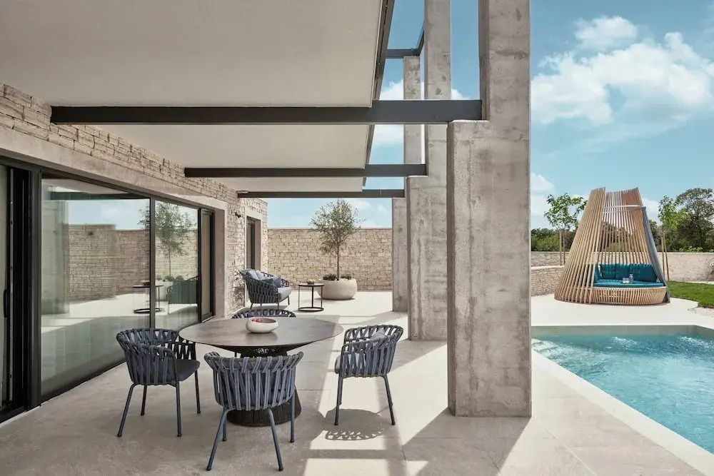 Moderne Terrasse mit Esstisch und Stühlen neben einem Pool.