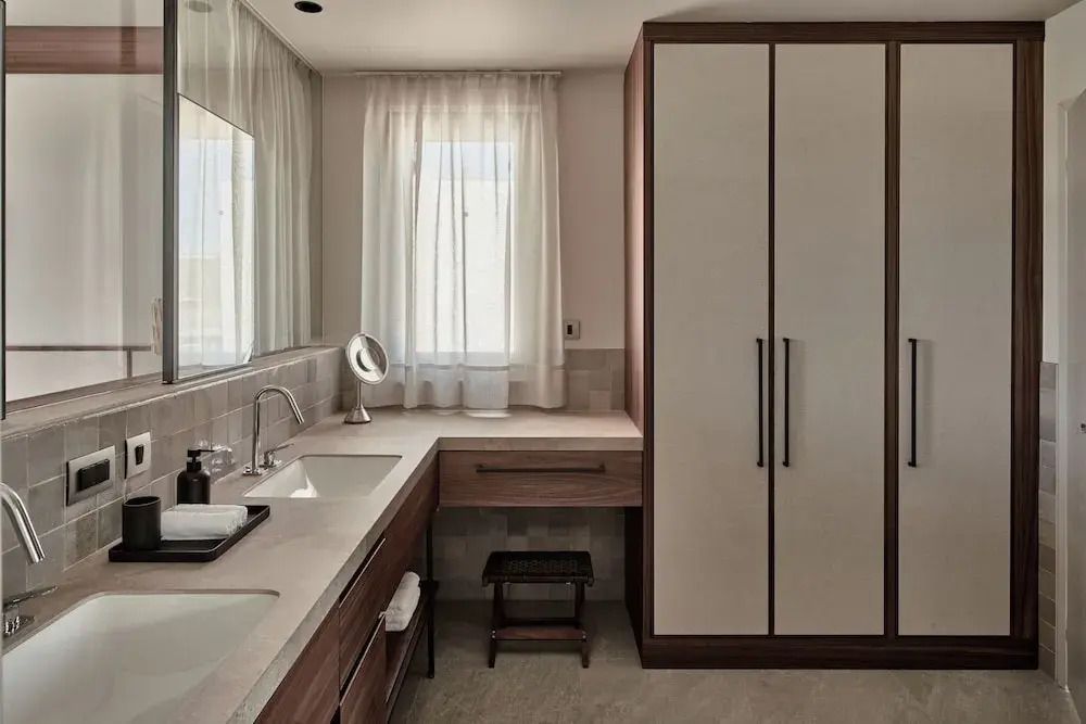 Helles Badezimmer mit Doppelwaschbecken und großem Schrank.